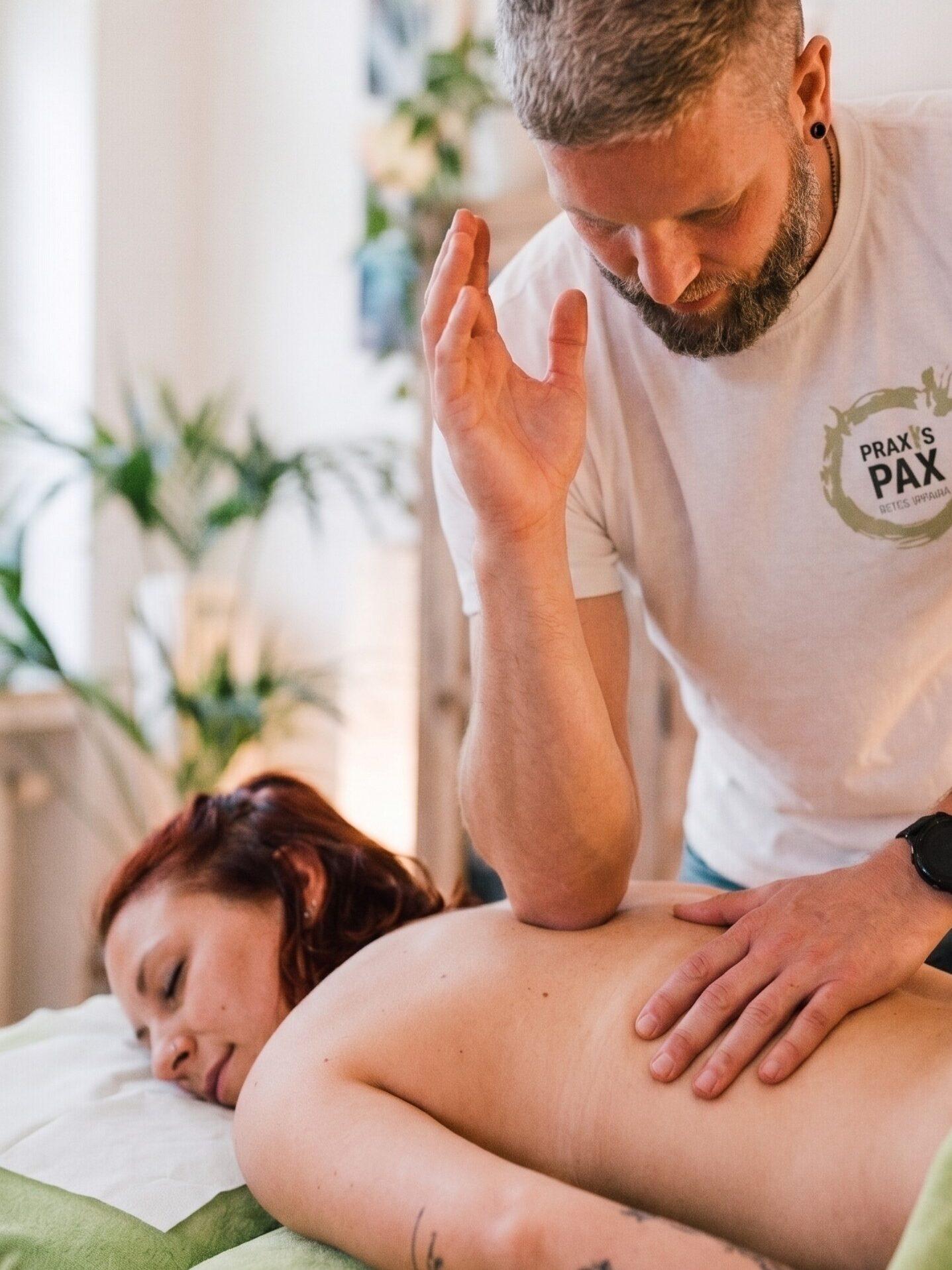 Fasziale Therapiebehandlung bei einer Patientin auf deren Rücken